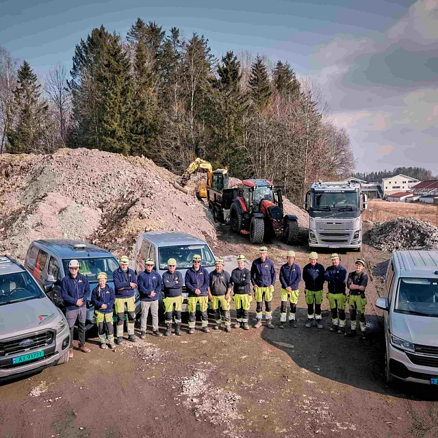 En gruppe mennesker ved siden av hverandre mellom arbeidsbiler